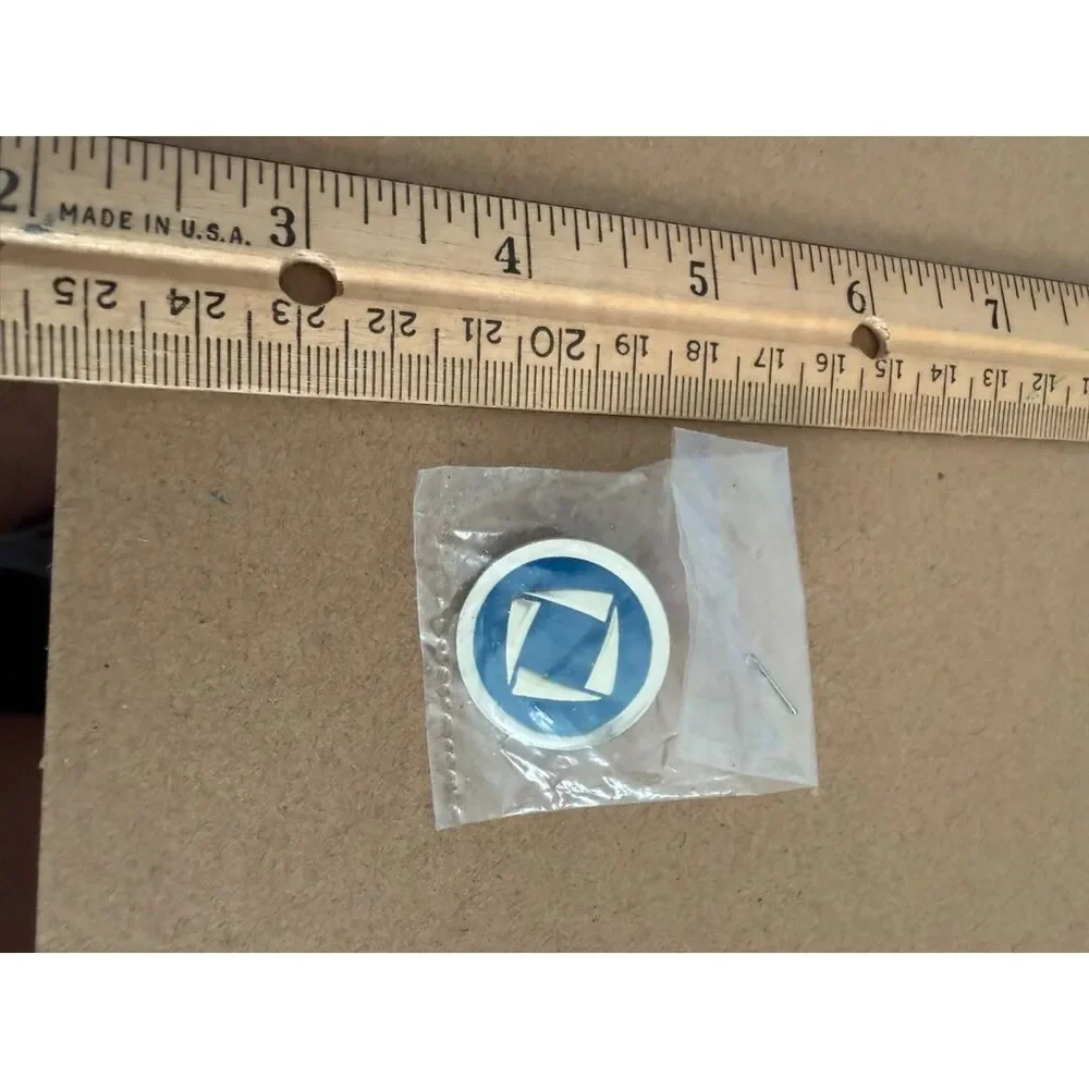 DECA logo pin  round white rim blue center with white shapes